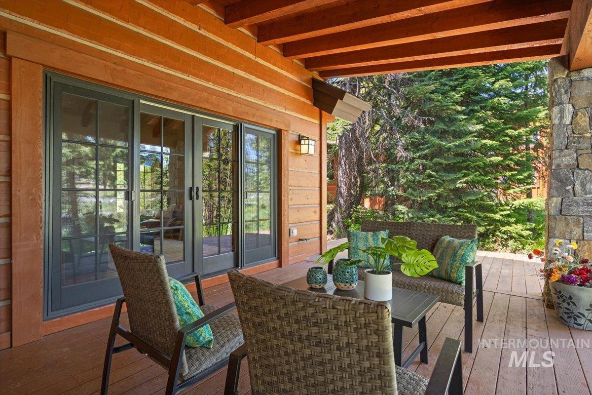 Covered outdoor patio featuring wood-finish flooring, exposed wood beam ceiling, and a stone accent column