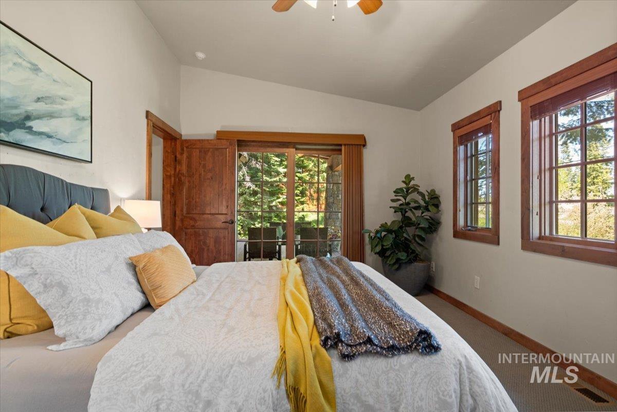 Bedroom featuring vaulted ceilings, wood-framed windows, and a sliding glass door leading to an exterior space