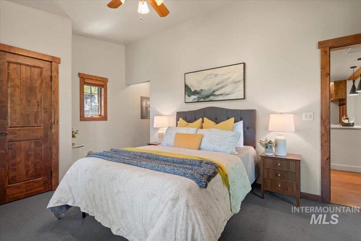 Vaulted ceiling bedroom featuring dark carpet, a wood-finish door, and a wood-framed window