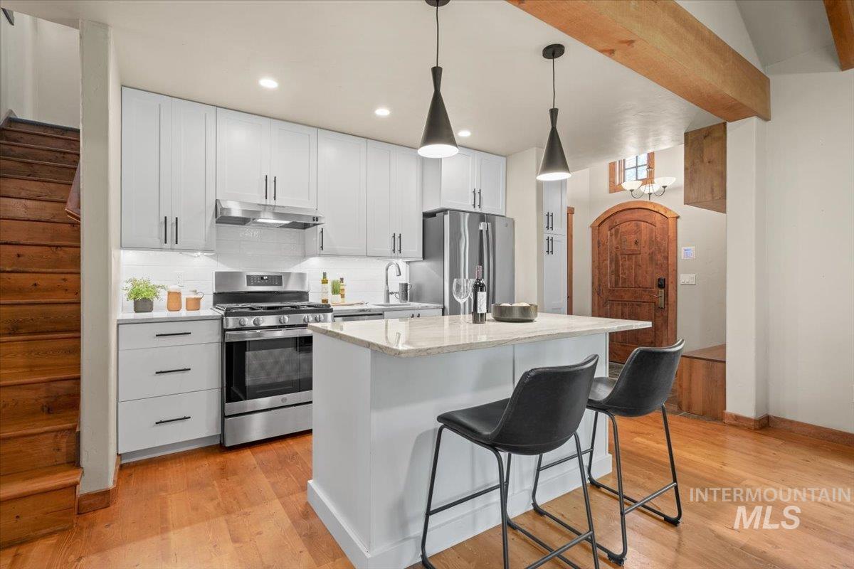 Contemporary kitchen featuring light gray cabinetry, stainless steel appliances, and a central island with countertop seating