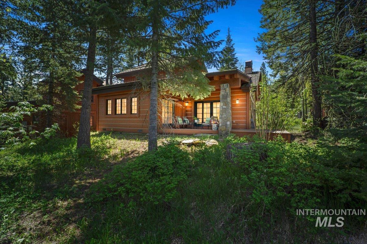 Wood-clad home with a stone-clad chimney and exposed log pillar