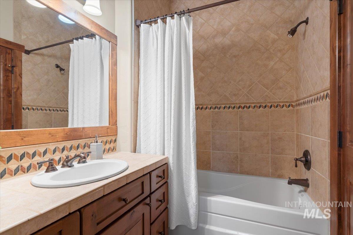 Bathroom with integrated shower and tub featuring neutral-toned tile surrounds with a decorative accent band