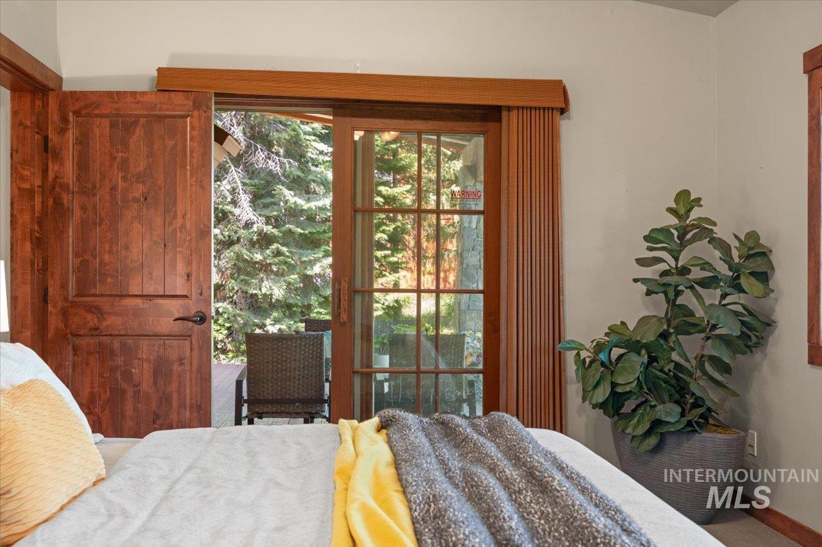 Wood-paneled door with dark hardware, alongside a glass-paned sliding door, opening onto an exterior space with an outdoor chair