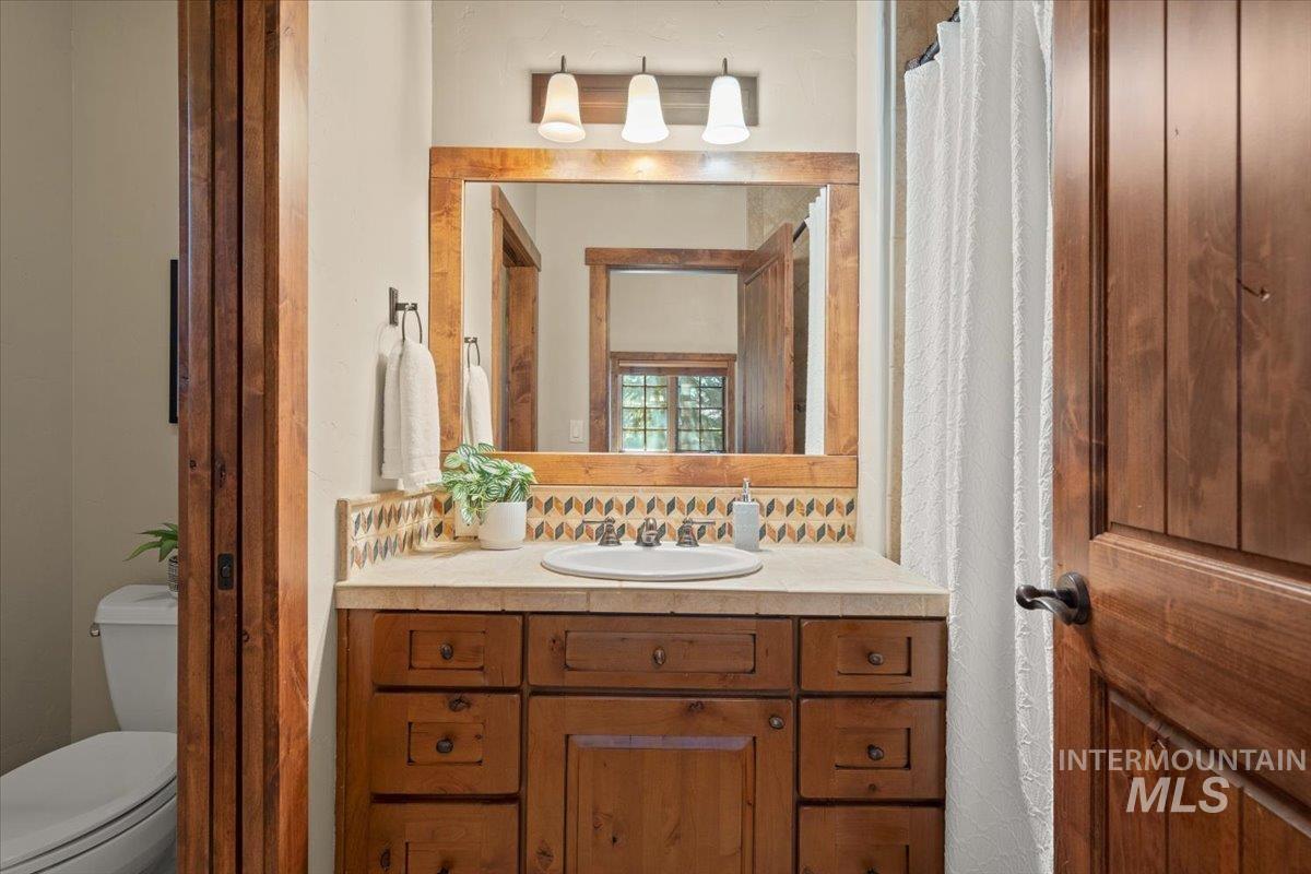 Warm wood-finish vanity with a light-toned countertop, under-mount sink, and custom tile backsplash