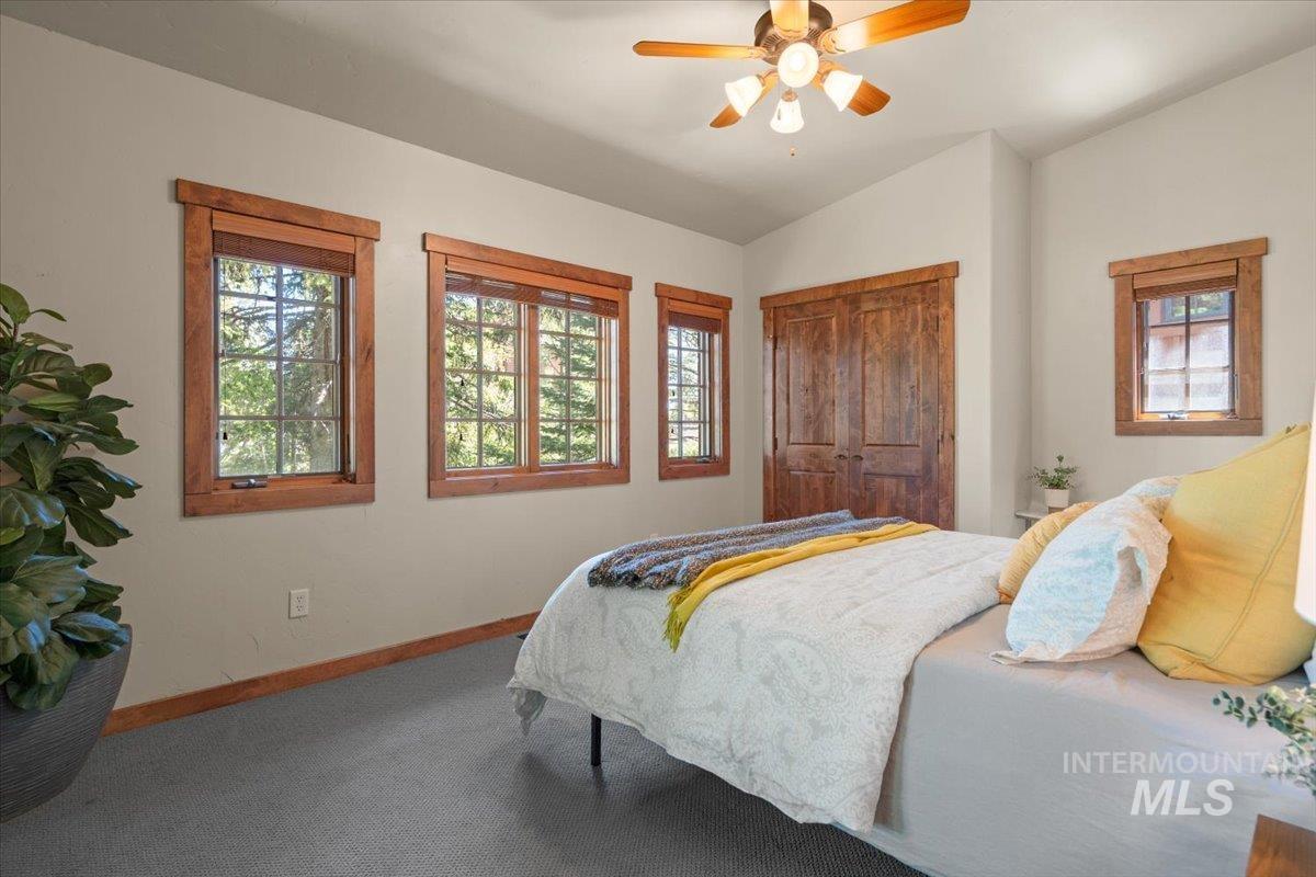 Room featuring wood-framed windows, a wood-finish closet door, a ceiling fan with light fixture, and light-toned walls