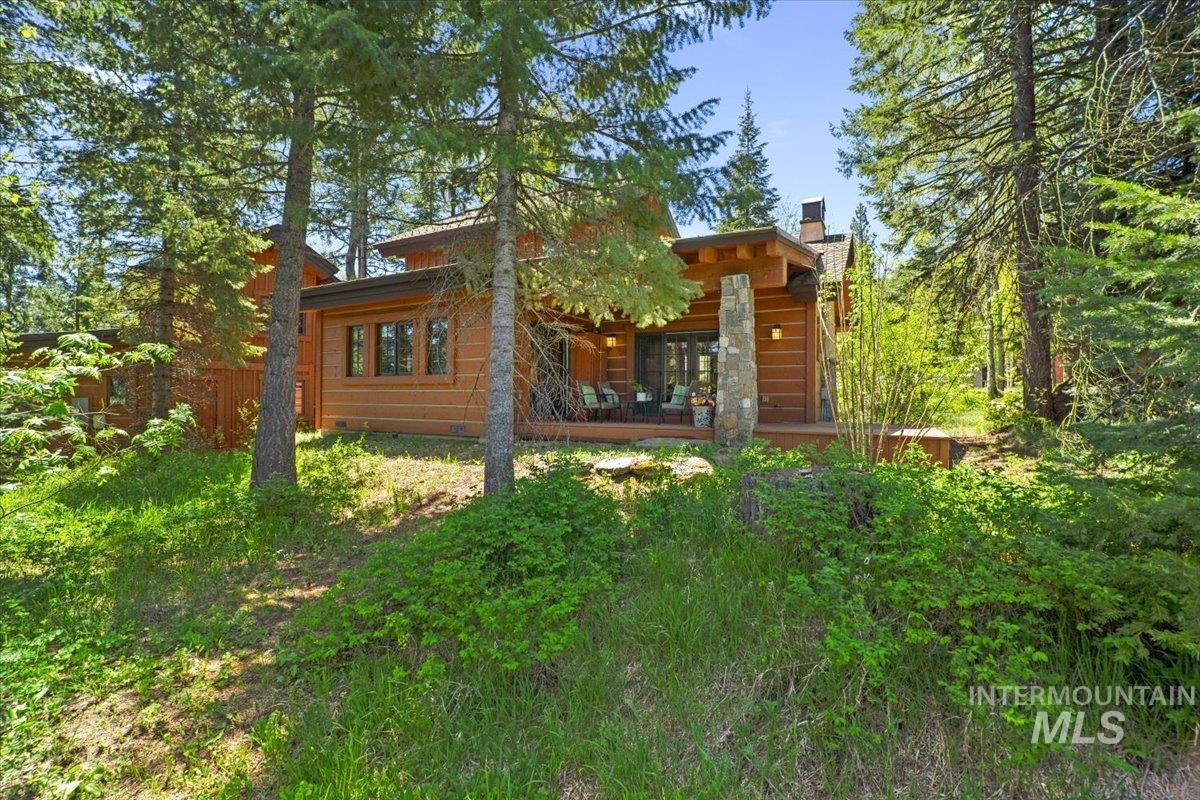 Wood-sided residence featuring a multi-level roofline, prominent stone-clad chimney, and a spacious outdoor deck
