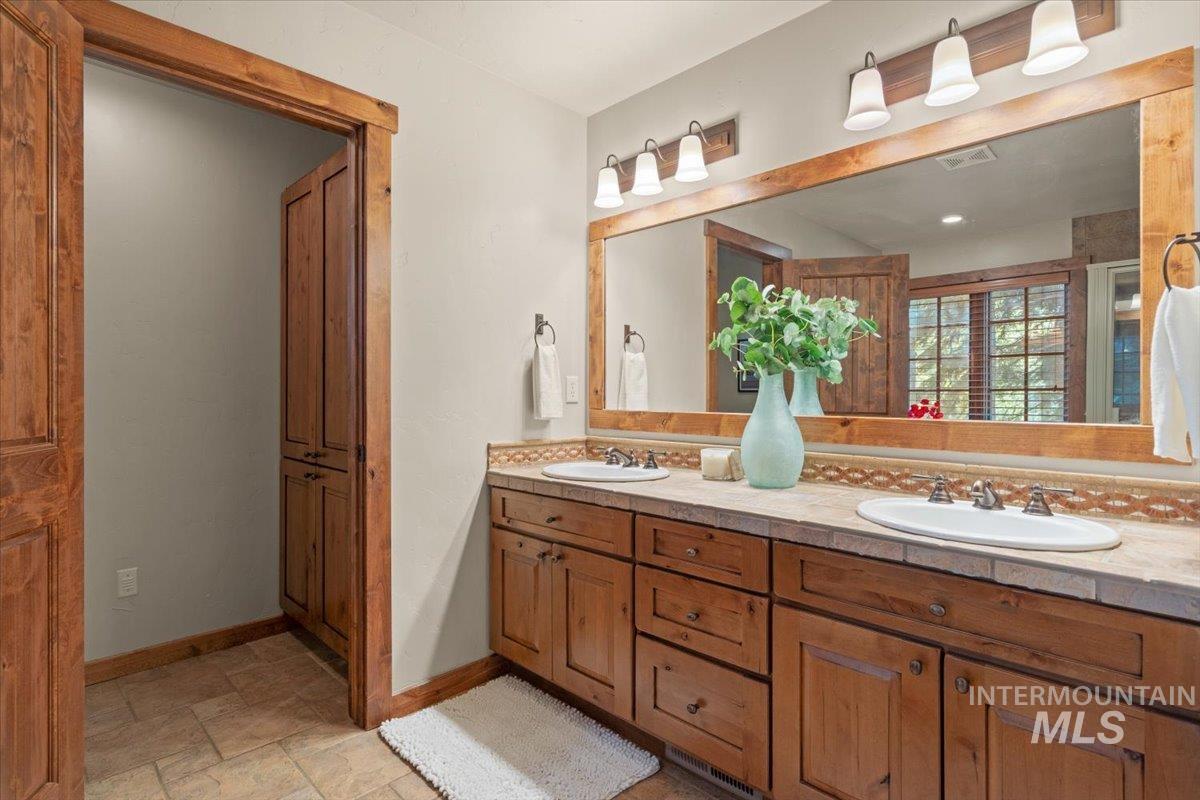 Double vanity with integrated sinks, stone-finish countertop, and wood-finish cabinetry