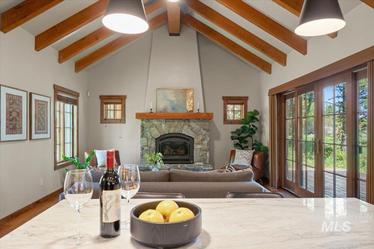 Vaulted ceilings with exposed wood beams highlight the stone fireplace with a wood mantel