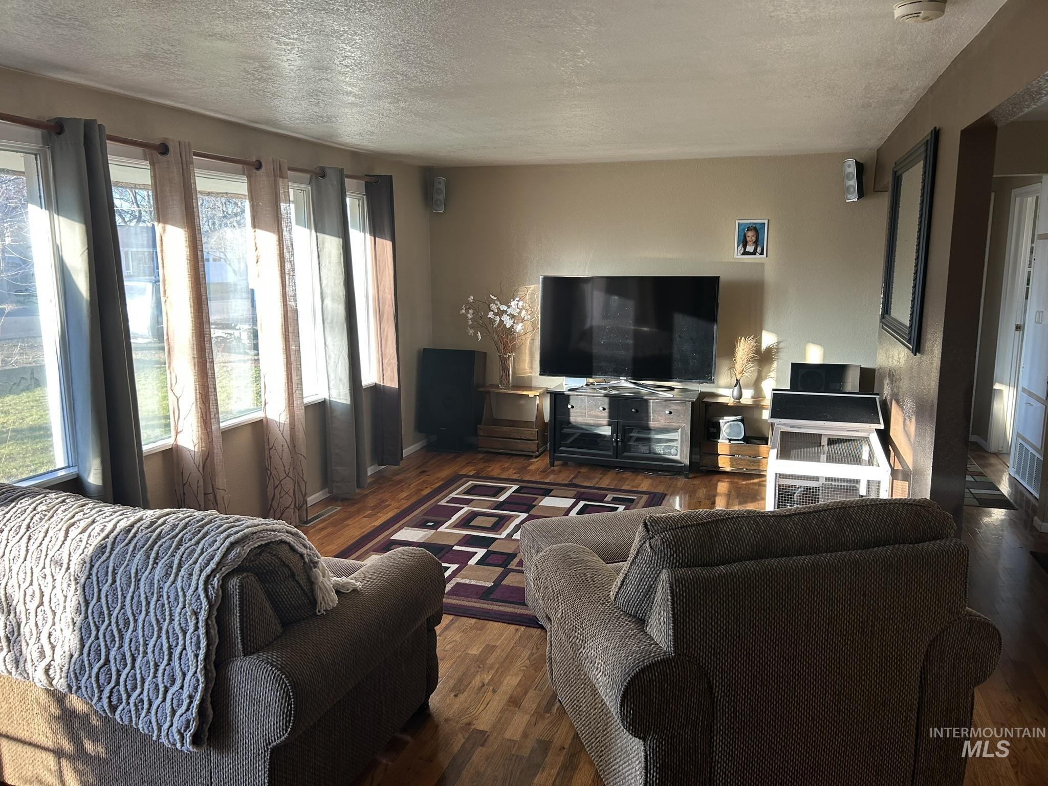 Living area with a textured ceiling and hardwood / wood-style floors