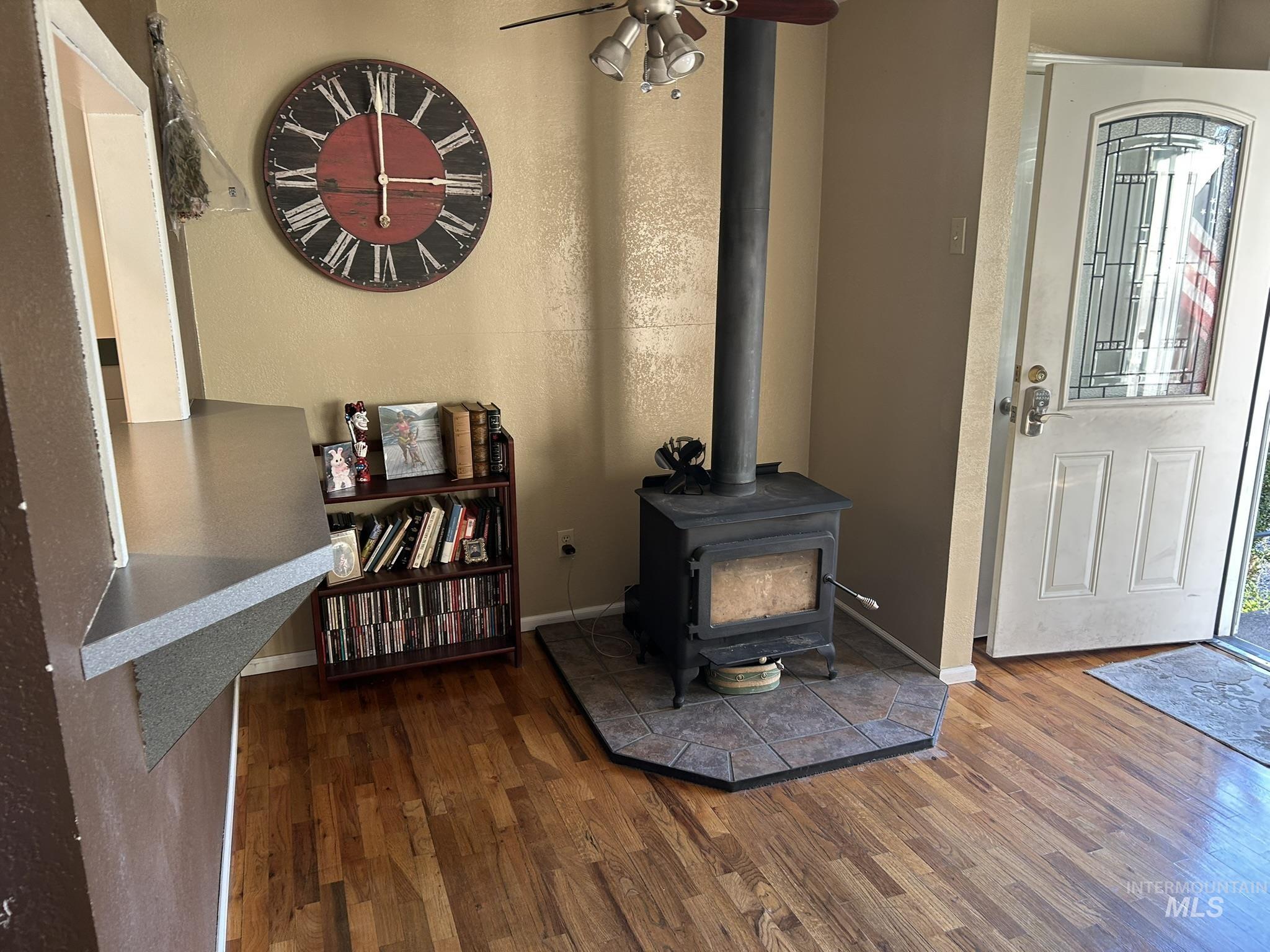Foyer entrance featuring a wood stove, wood finished floors, and a ceiling fan