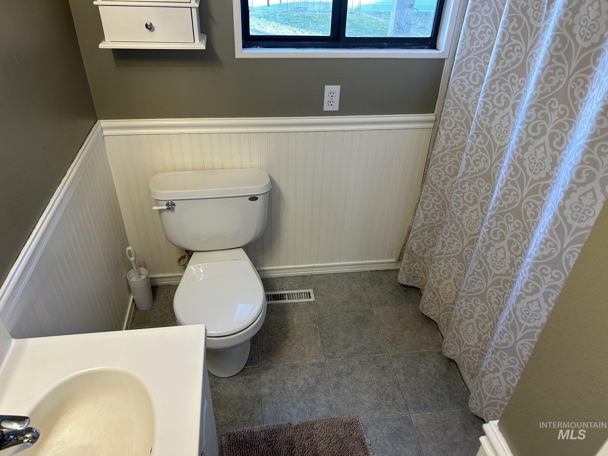 Bathroom with a wainscoted wall, a shower with curtain, and vanity