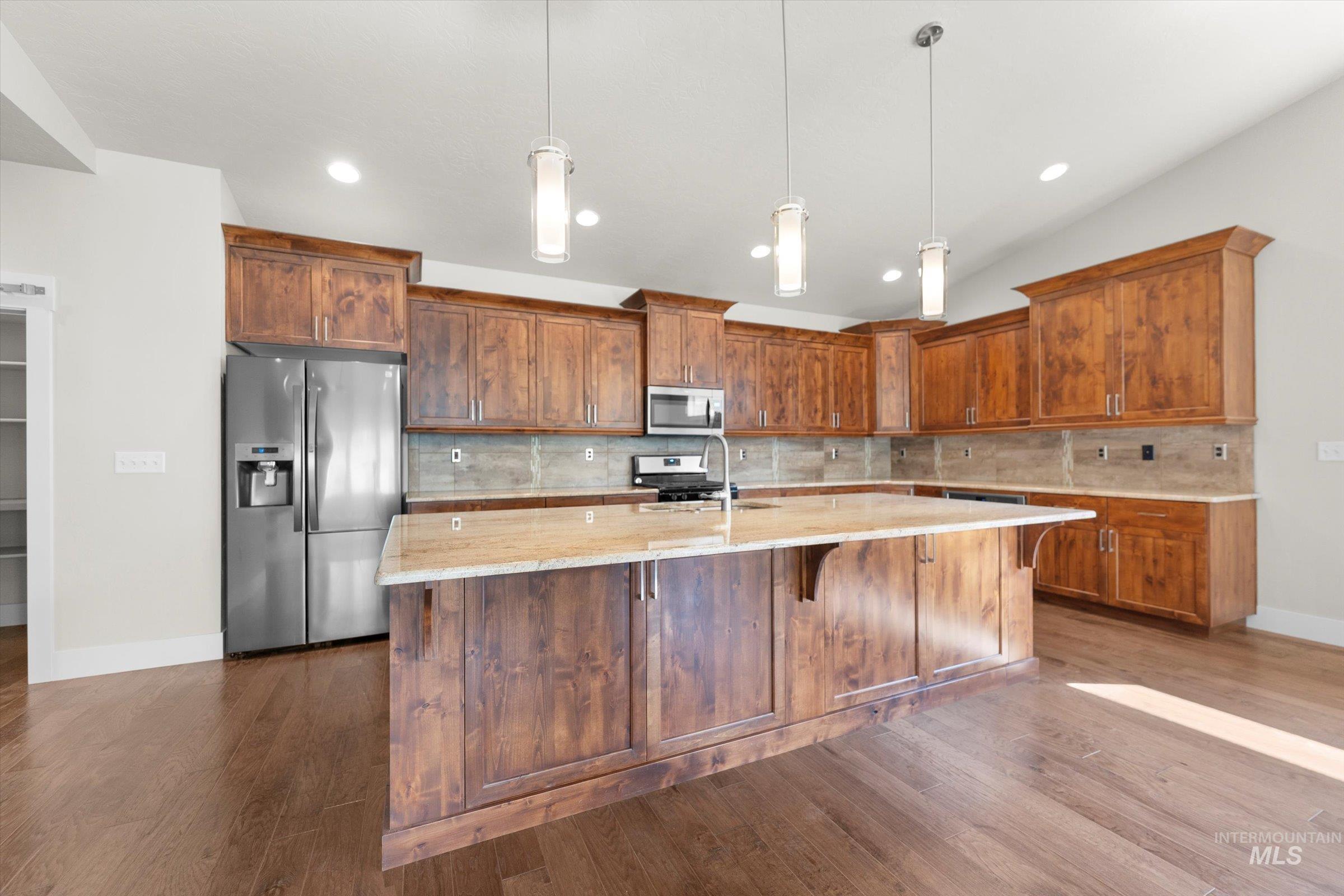 Kitchen featuring tasteful backsplash, appliances with stainless steel finishes, hanging light fixtures, and recessed lighting