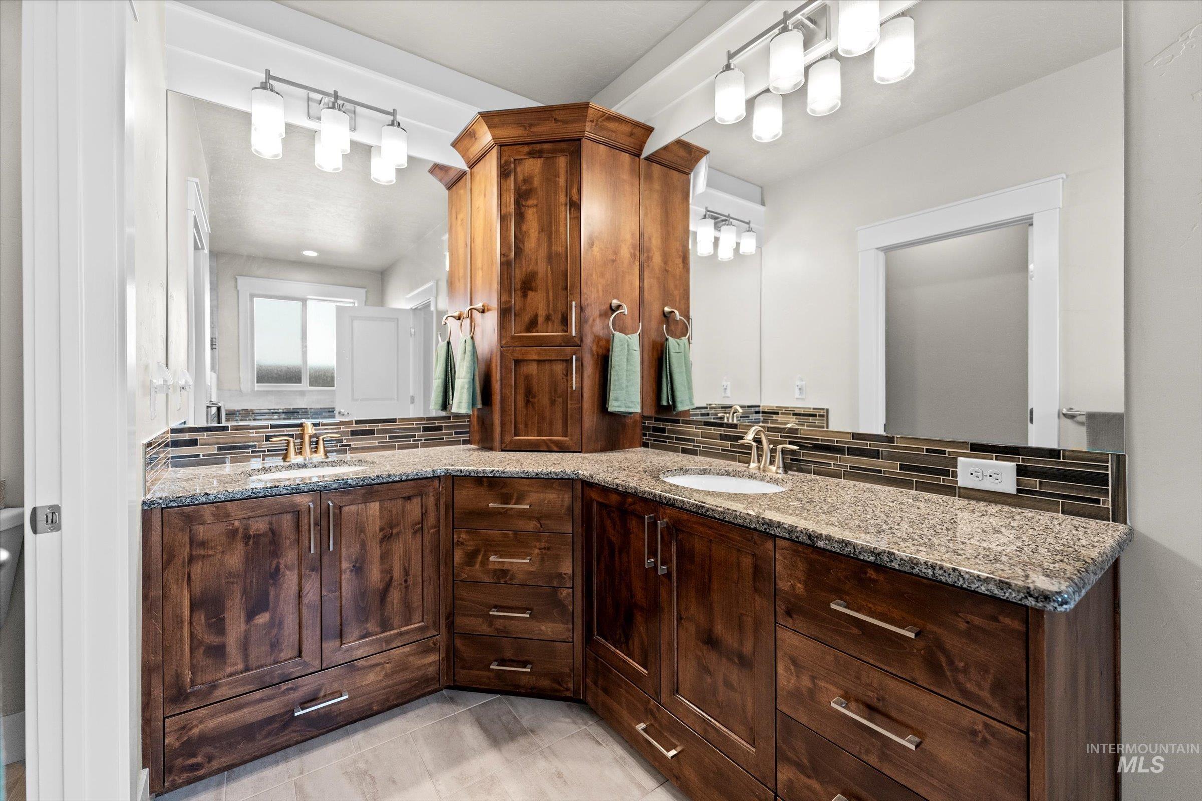 Bathroom with tasteful backsplash, double vanity, and light tile patterned flooring