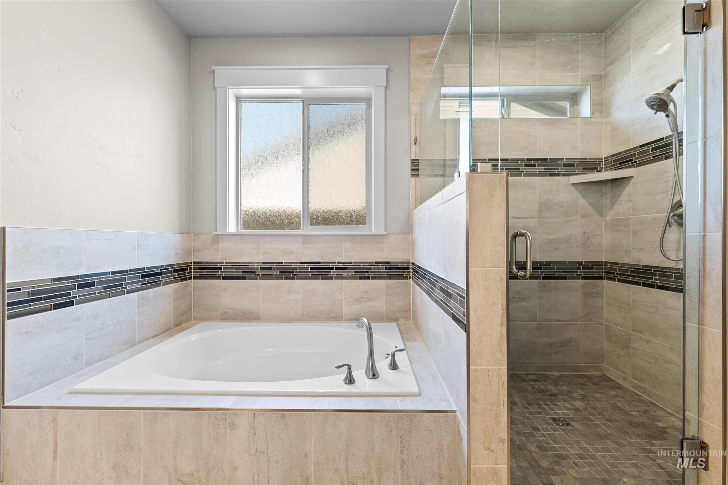 Full bath with plenty of natural light, a garden tub, and a stall shower