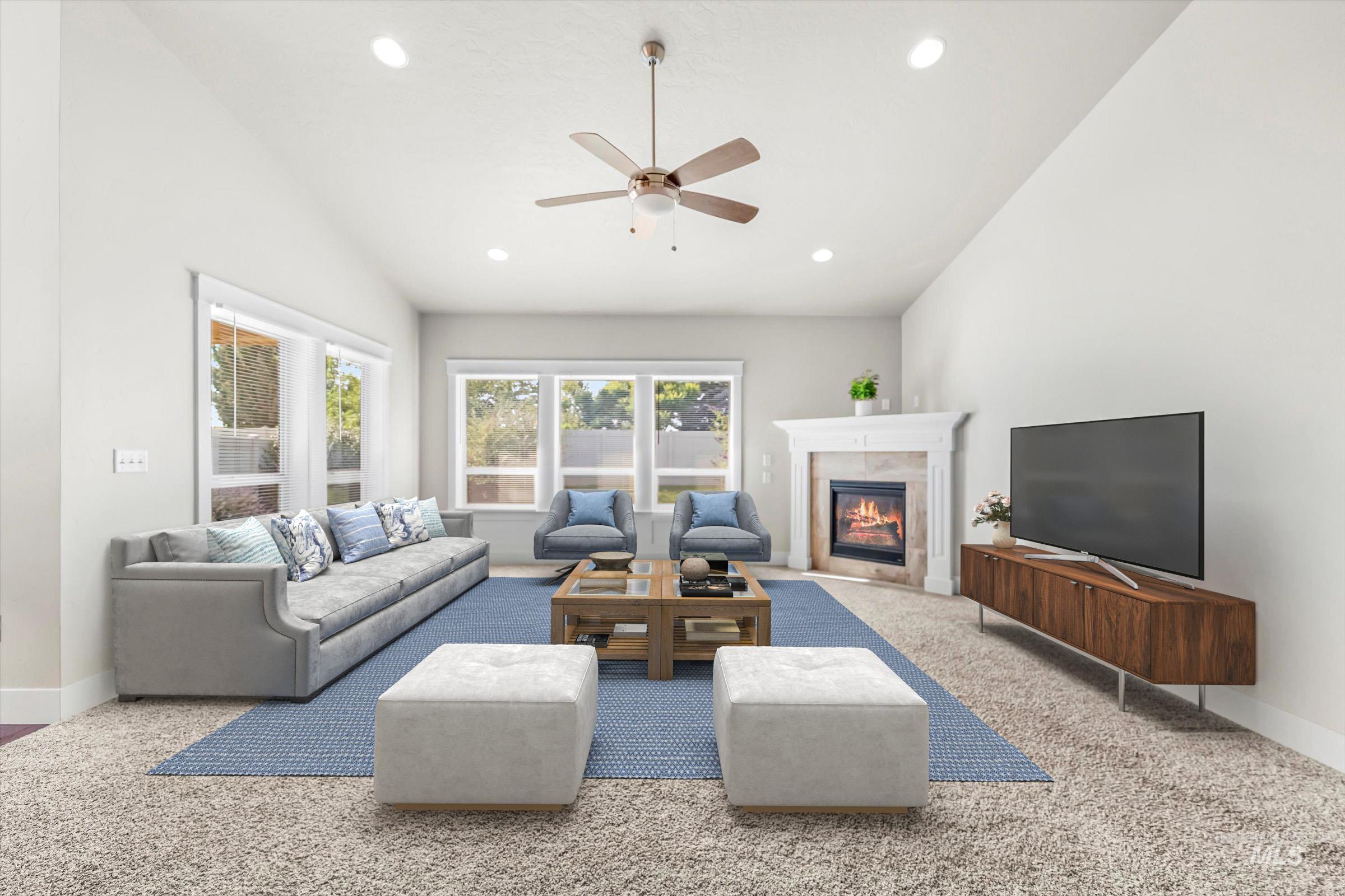 Living room with vaulted ceiling, a glass covered fireplace, recessed lighting, ceiling fan, and carpet flooring