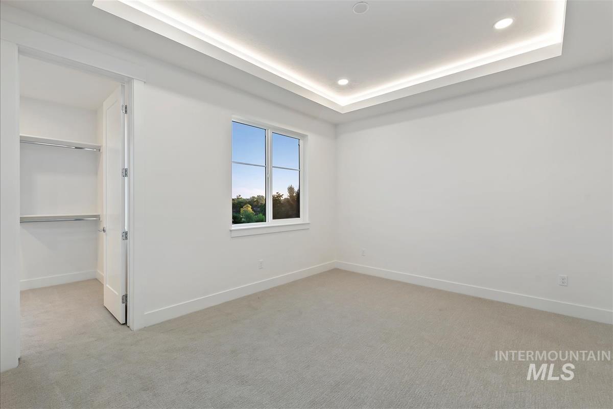 Bright interior space featuring recessed ceiling lighting, a tray ceiling, and a single window with outdoor scenery