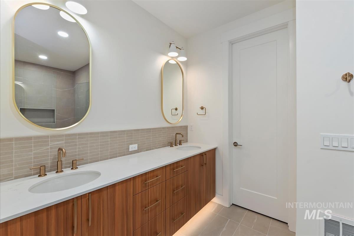 Dual oval mirrors with gold-tone frames above a wood-finish double vanity