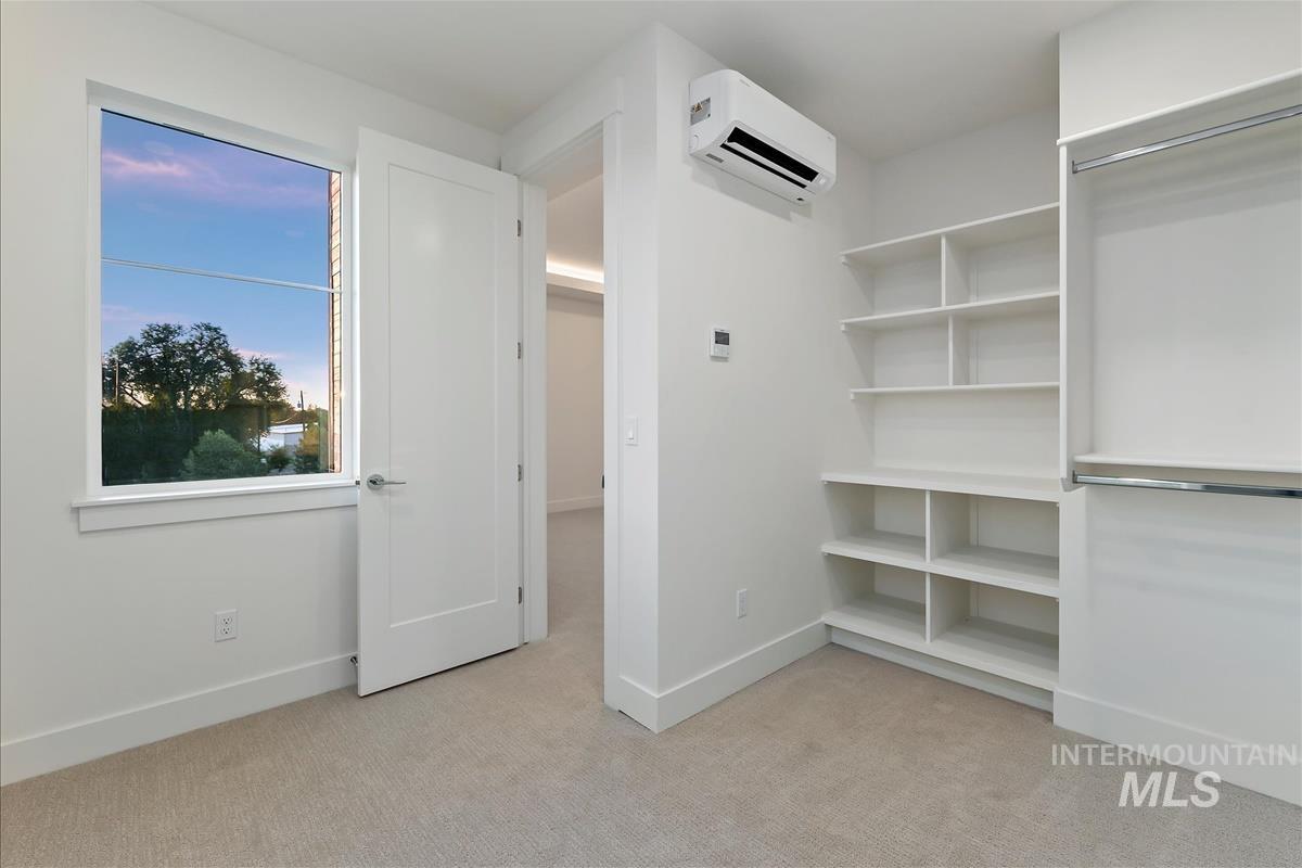 Built-in shelving and hanging rods complement the neutral carpet flooring