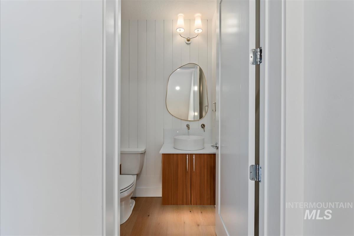 Bathroom featuring a wall-mounted vanity with a vessel sink, wood-finish cabinetry, and light wood-finish flooring