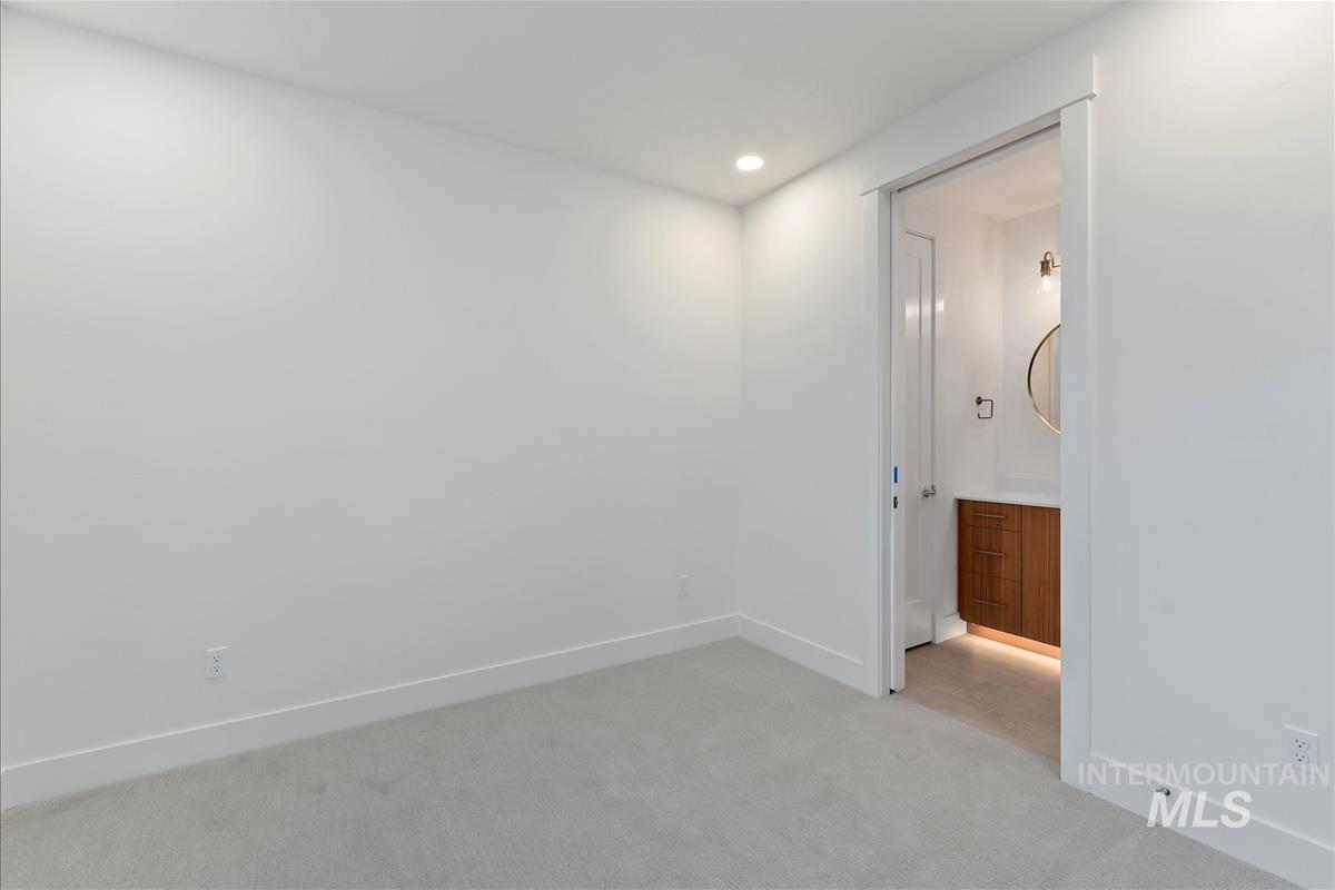 Room featuring light gray carpeting, recessed ceiling lighting, and a pocket door opening to a bathroom