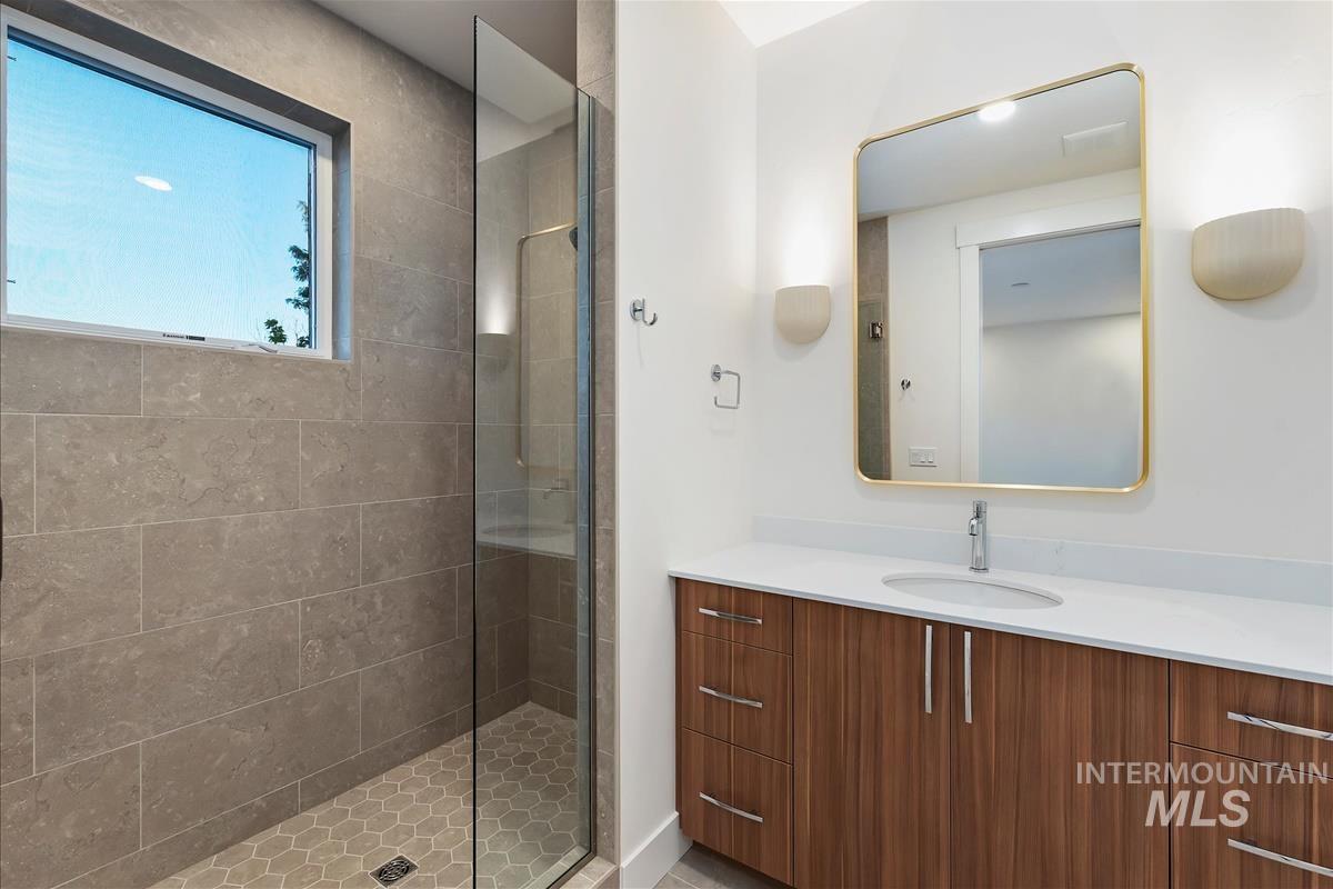 Modern bathroom featuring a glass-enclosed shower with large format wall tiles and hexagonal floor tiles