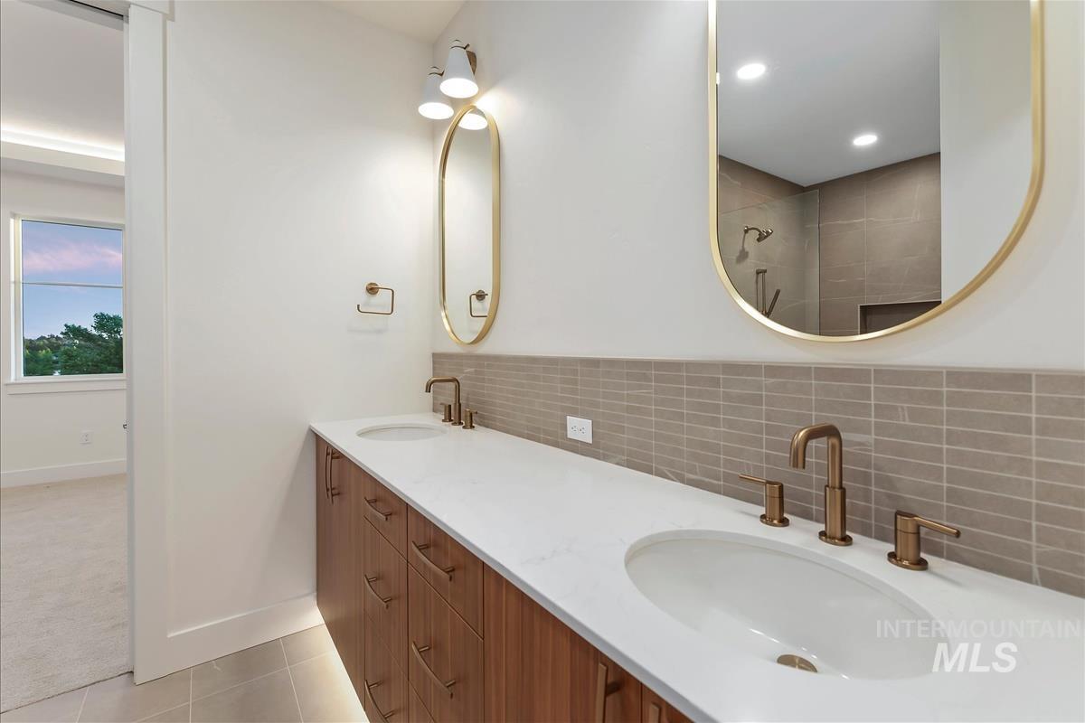 Bathroom featuring a dual vanity with wood-finish cabinetry, white countertops, and bronze-tone fixtures