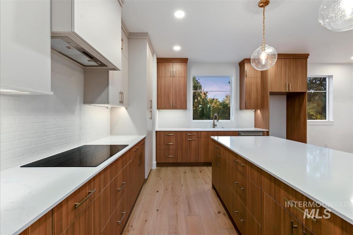 Contemporary kitchen featuring light wood-finish flooring, white countertops, and a full suite of built-in cabinetry