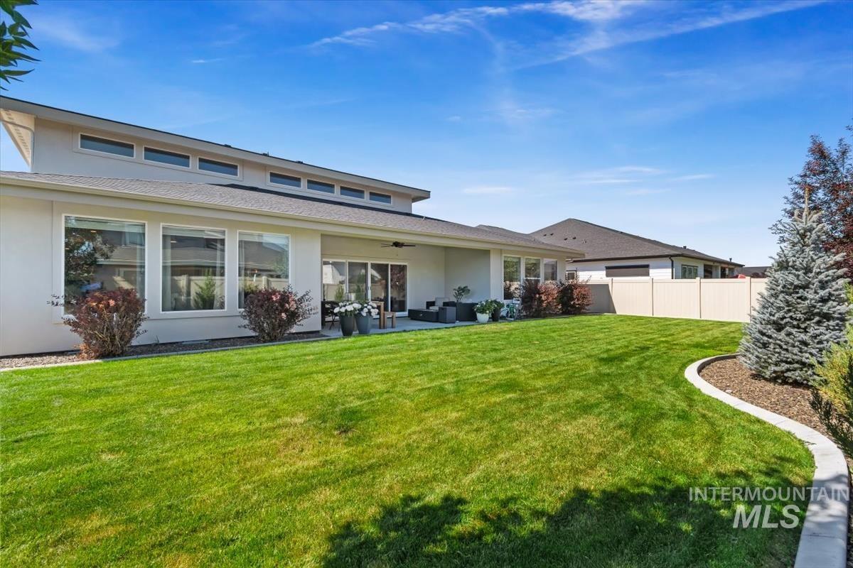 Expansive backyard featuring a manicured lawn, a concrete patio, and mature landscaping