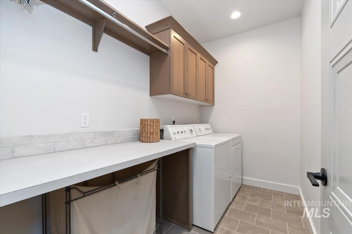 Laundry area featuring a long countertop, upper cabinetry, and a clothing rod