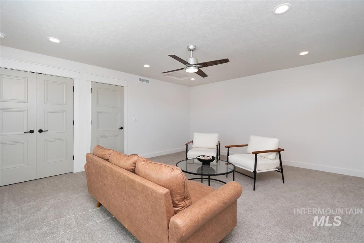 Spacious room featuring light gray carpeting, recessed ceiling lighting, a modern ceiling fan, and paneled interior doors with matte black hardware
