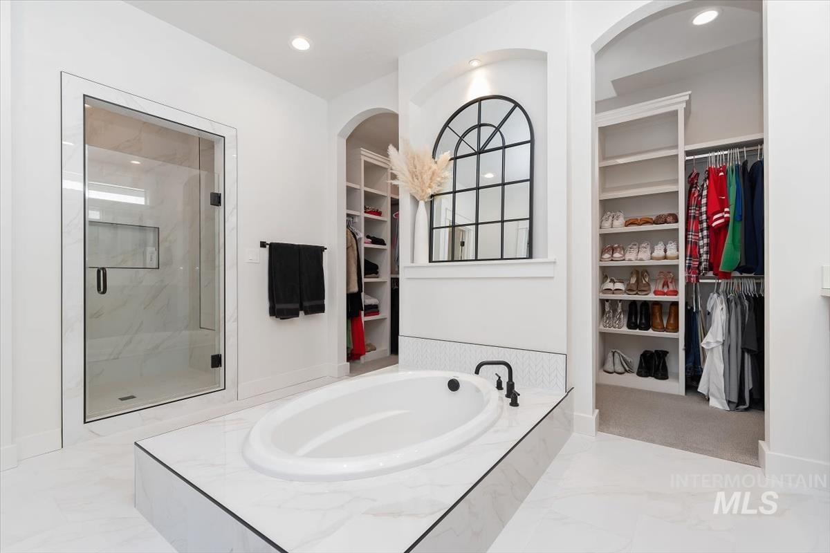 Soaking tub with matte black fixtures, set into a marble-finish platform