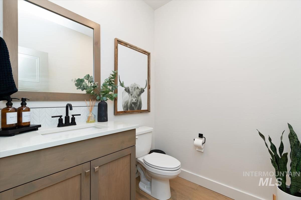 Vanity with light wood-finish cabinetry, white countertop, and matte black faucet