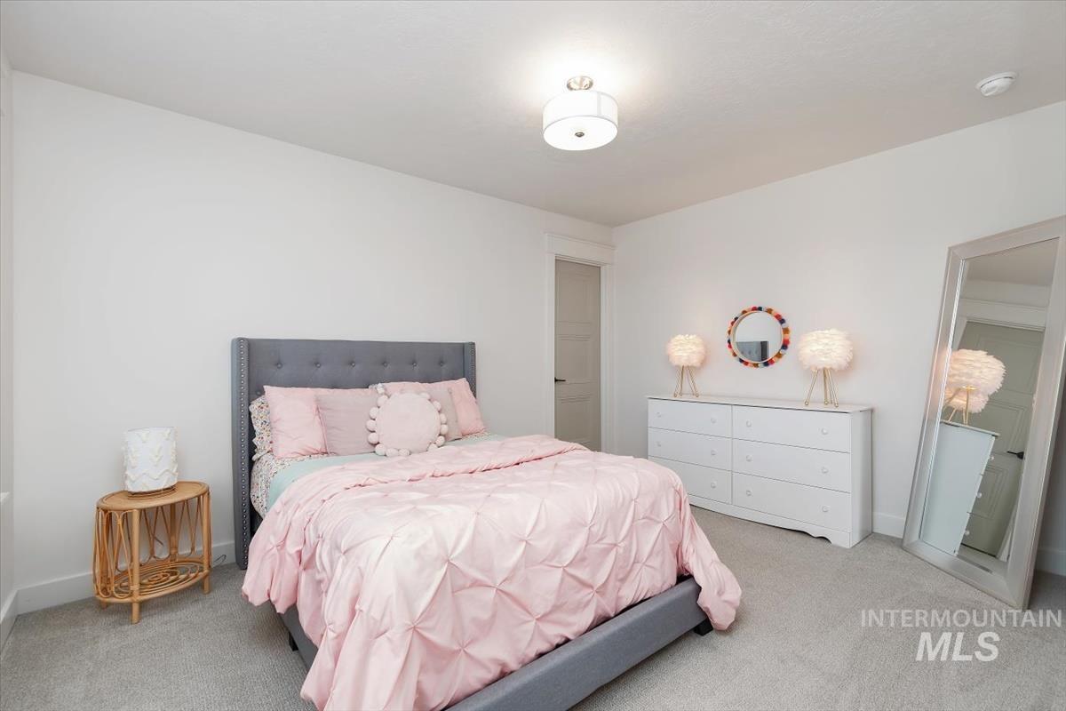 Well-lit room featuring neutral wall paint, light gray carpeting, a built-in white dresser, and a ceiling-mounted light fixture