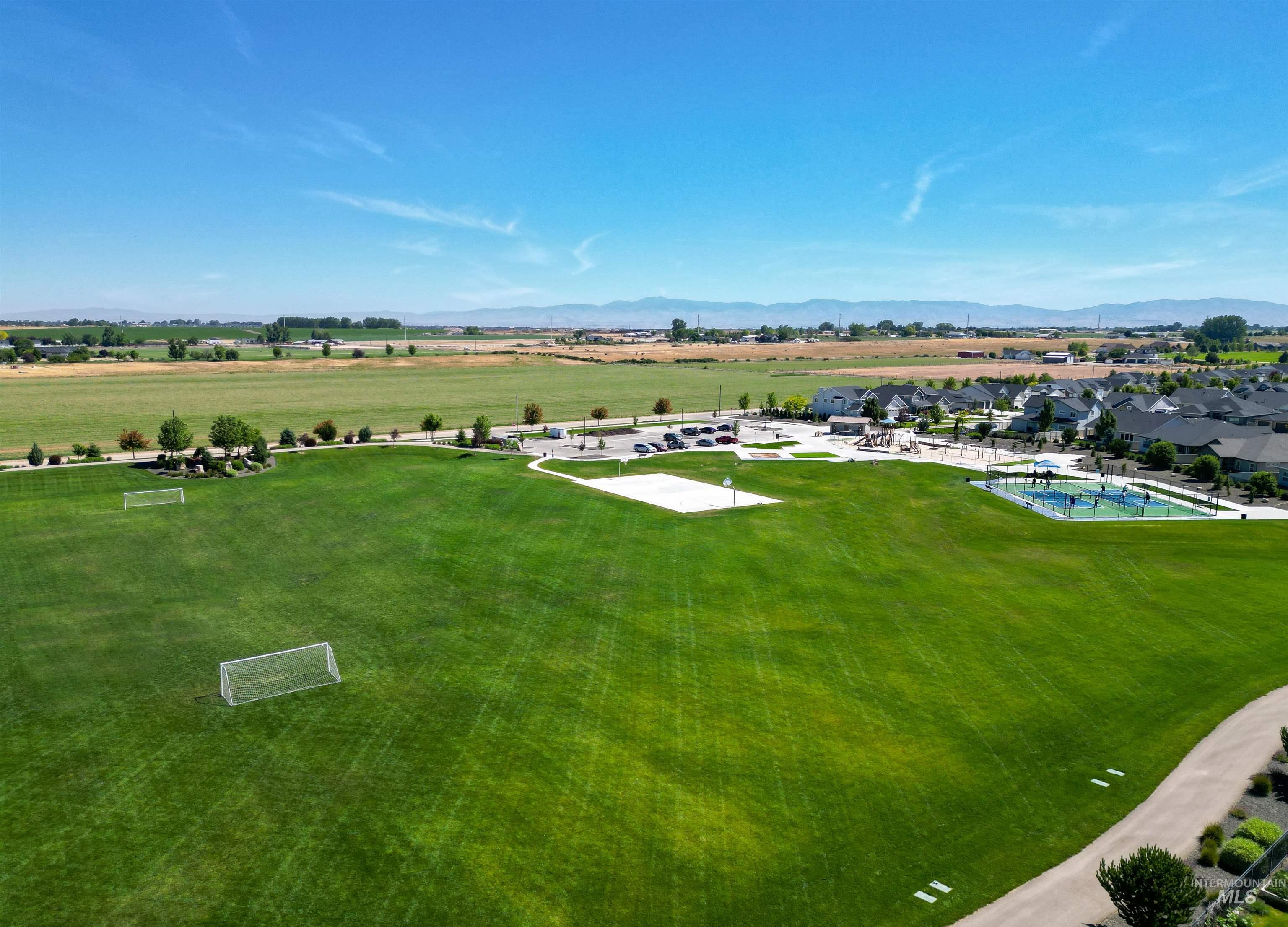 Expansive green space featuring multiple soccer goals, a sand volleyball court, and a pickleball court