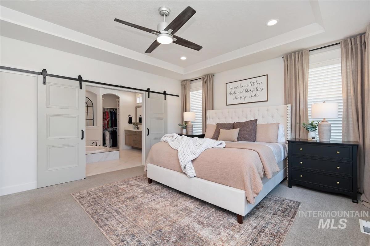 Carpeted bedroom with a tray ceiling and recessed lighting