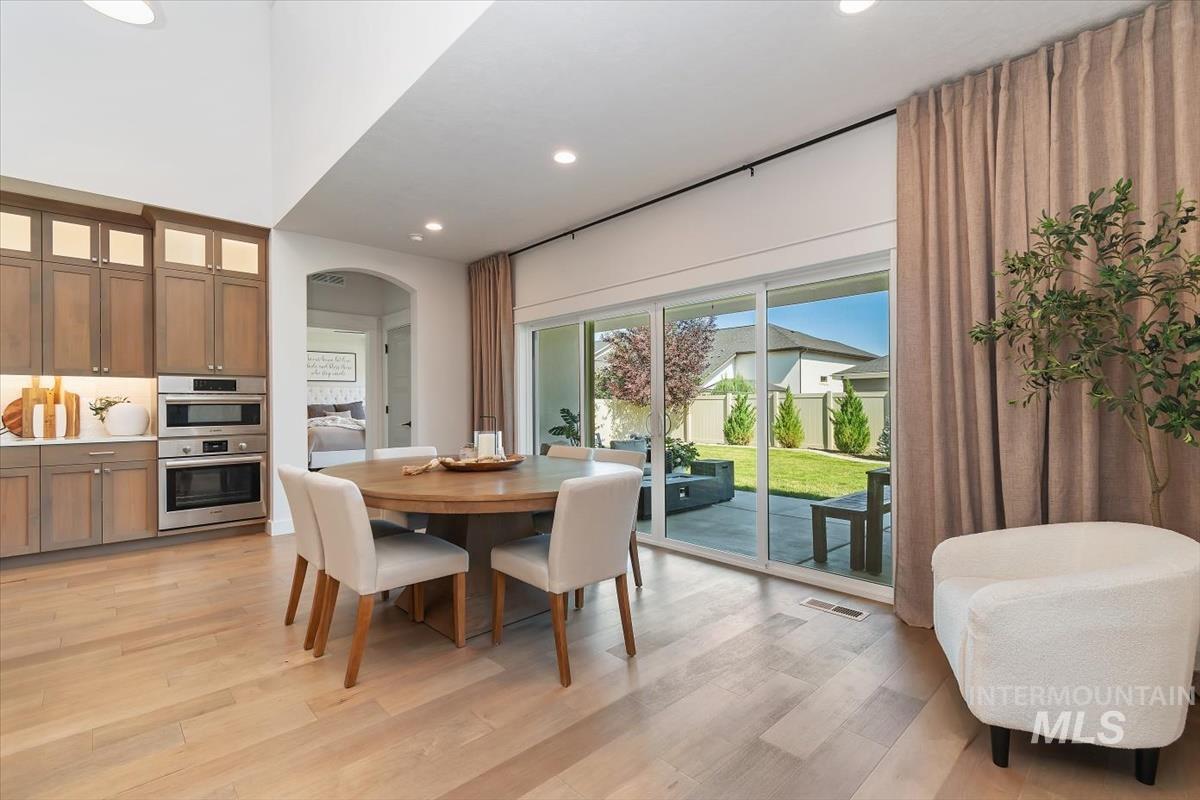 Dining area featuring light wood-finish flooring and a vaulted ceiling