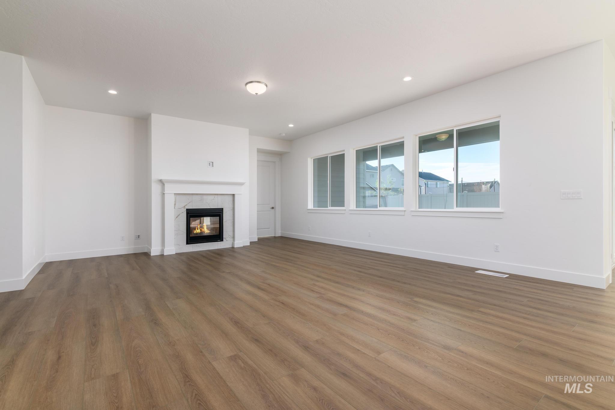 Unfurnished living room featuring a tile fireplace, wood finished floors, and recessed lighting