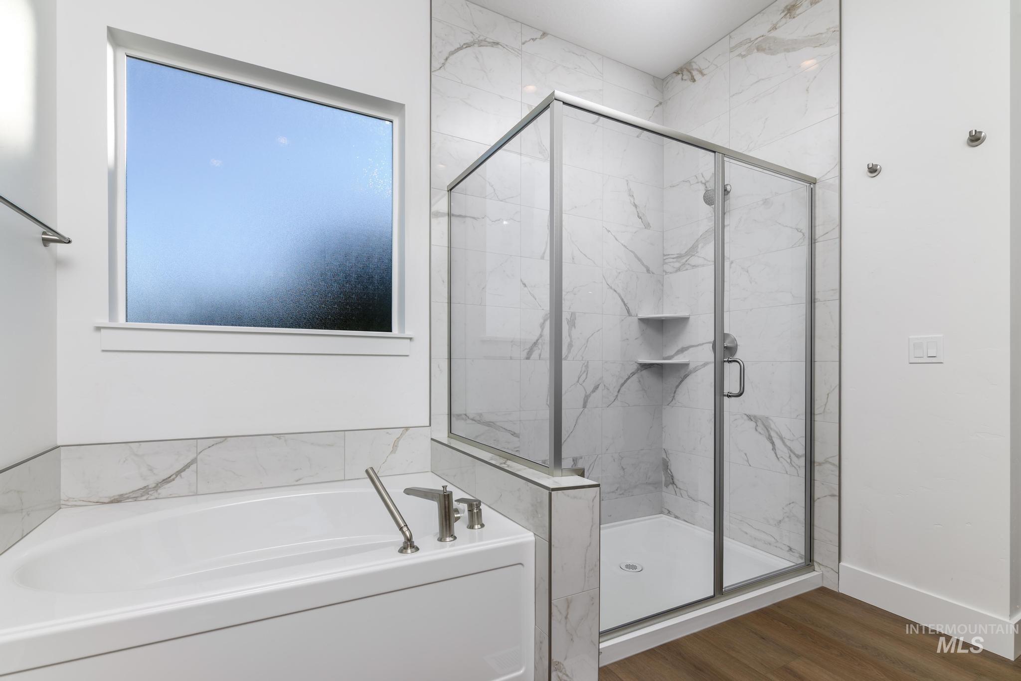 Full bathroom featuring a bath, a marble finish shower, and dark wood finished floors