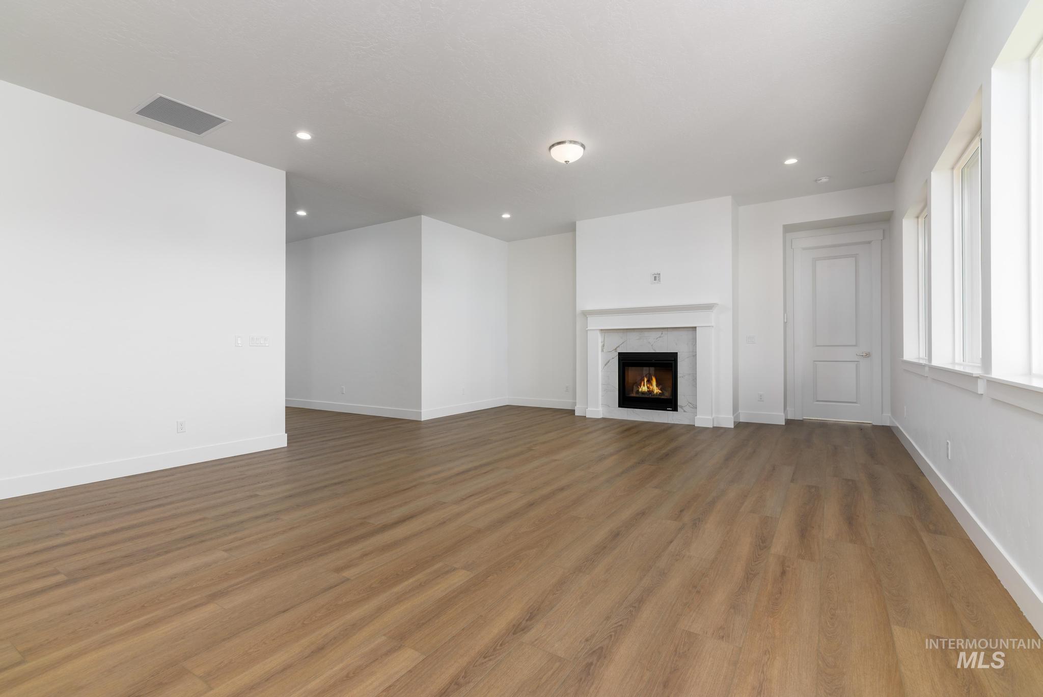 Unfurnished living room featuring a premium fireplace, recessed lighting, and light wood-style floors