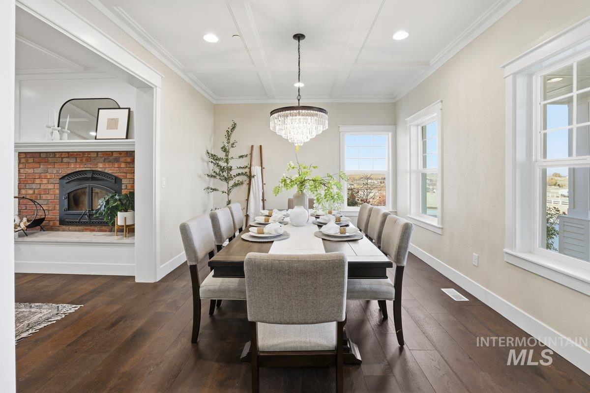 Dining area featuring dark wood-type flooring, a fireplace, coffered ceiling, recessed lighting, and crown molding
