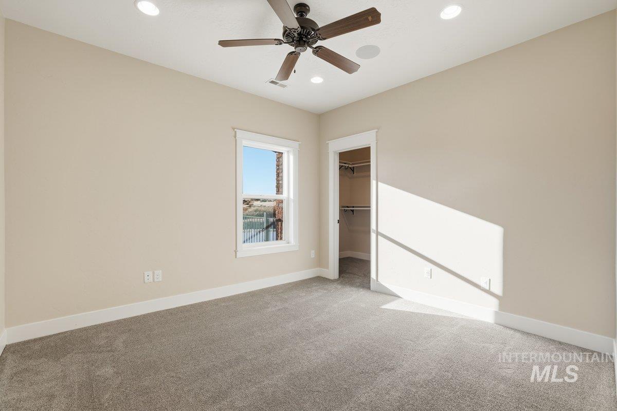 Unfurnished bedroom with carpet, recessed lighting, a spacious closet, and a ceiling fan