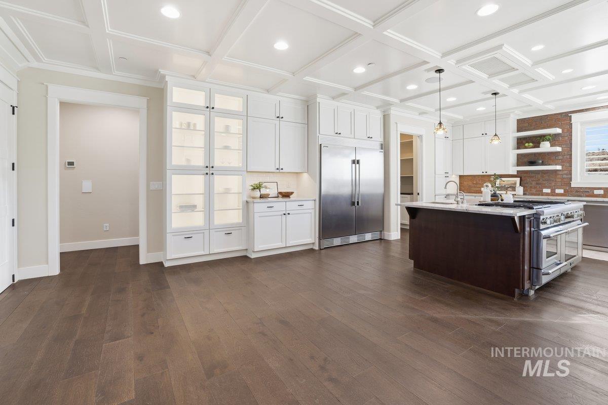 Kitchen with white cabinets, open shelves, premium appliances, decorative light fixtures, and beamed ceiling