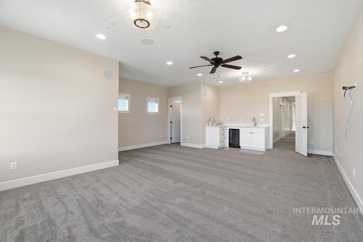Unfurnished living room featuring light colored carpet, recessed lighting, wine cooler, and a ceiling fan