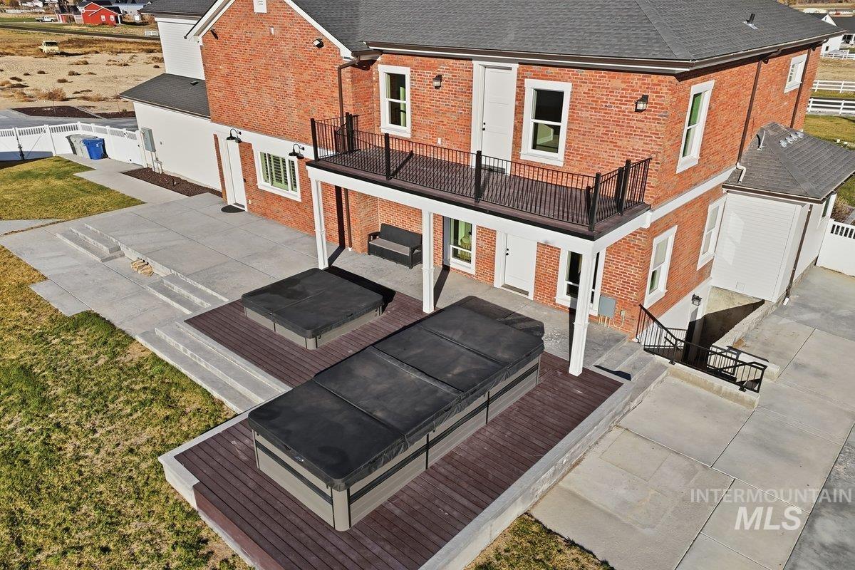 Back of property with a covered hot tub, brick siding, a fenced backyard, and a patio
