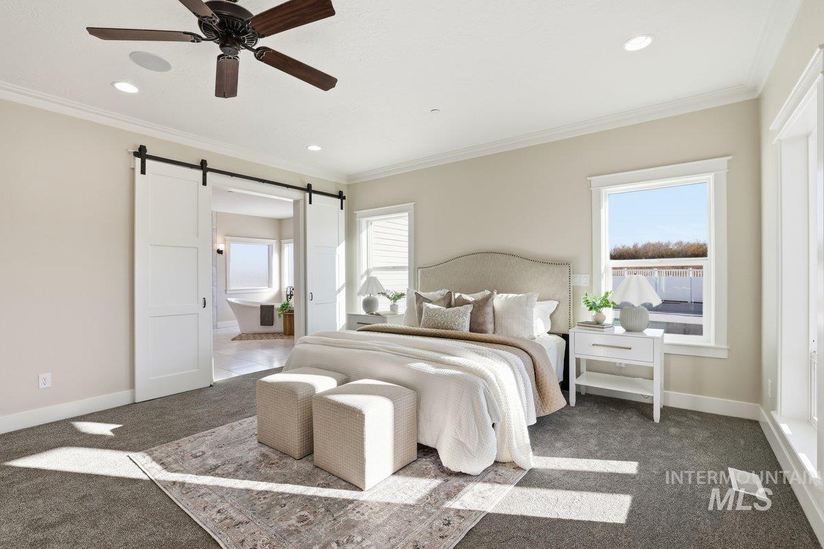 Bedroom with crown molding, carpet floors, a barn door, ensuite bath, and ceiling fan