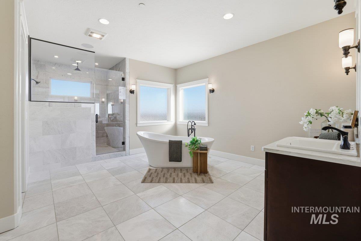 Bathroom featuring plenty of natural light, a freestanding bath, double vanity, a shower stall, and recessed lighting