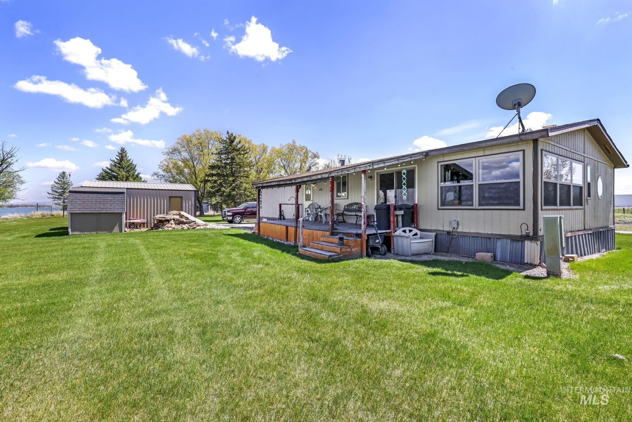 Rear view of house featuring a wooden deck, a yard, and an outbuilding