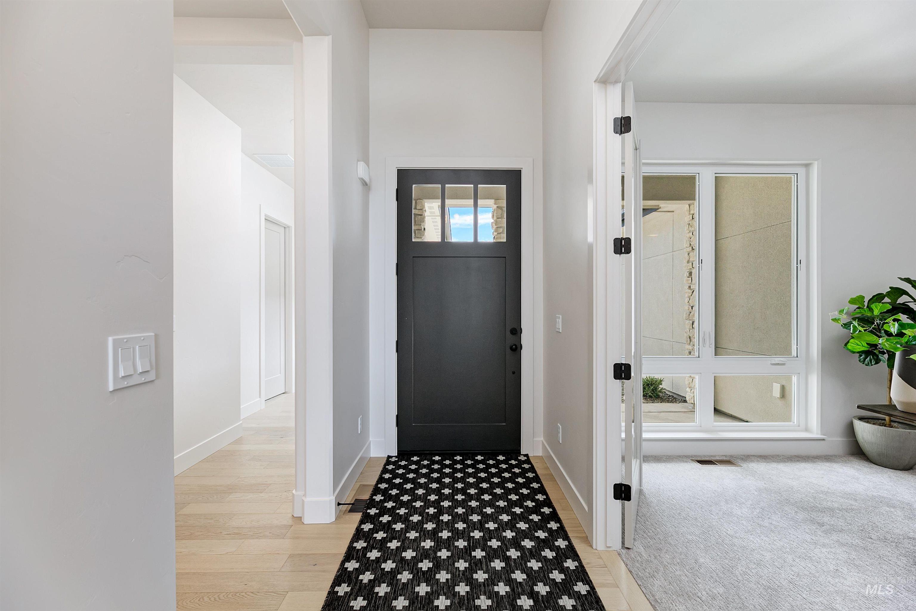 Entryway featuring a solid black door with transom window, wood-finish flooring, and white baseboards