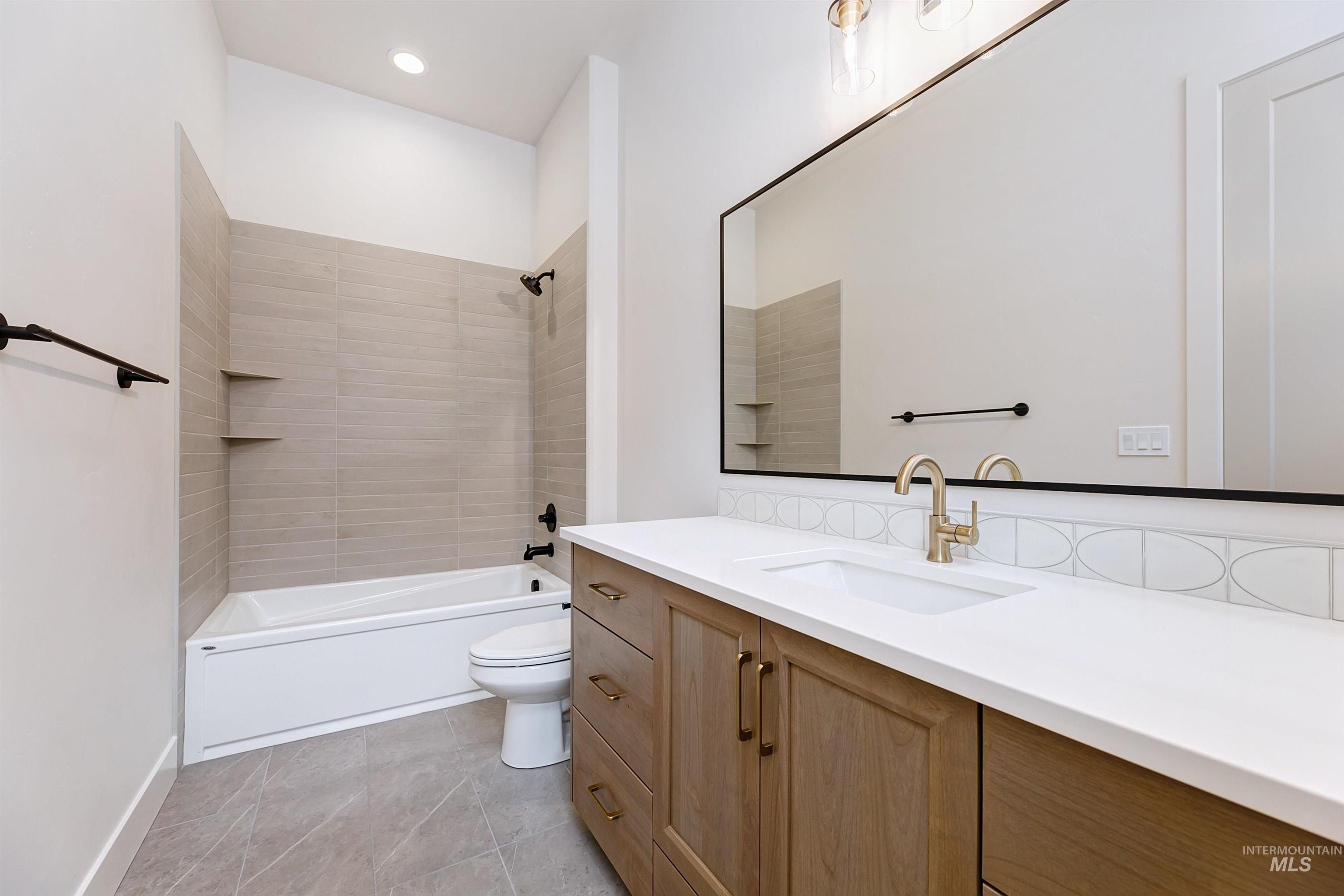 Bathroom vanity featuring a light wood-finish cabinet, white countertop with an integrated sink, and brushed gold faucet