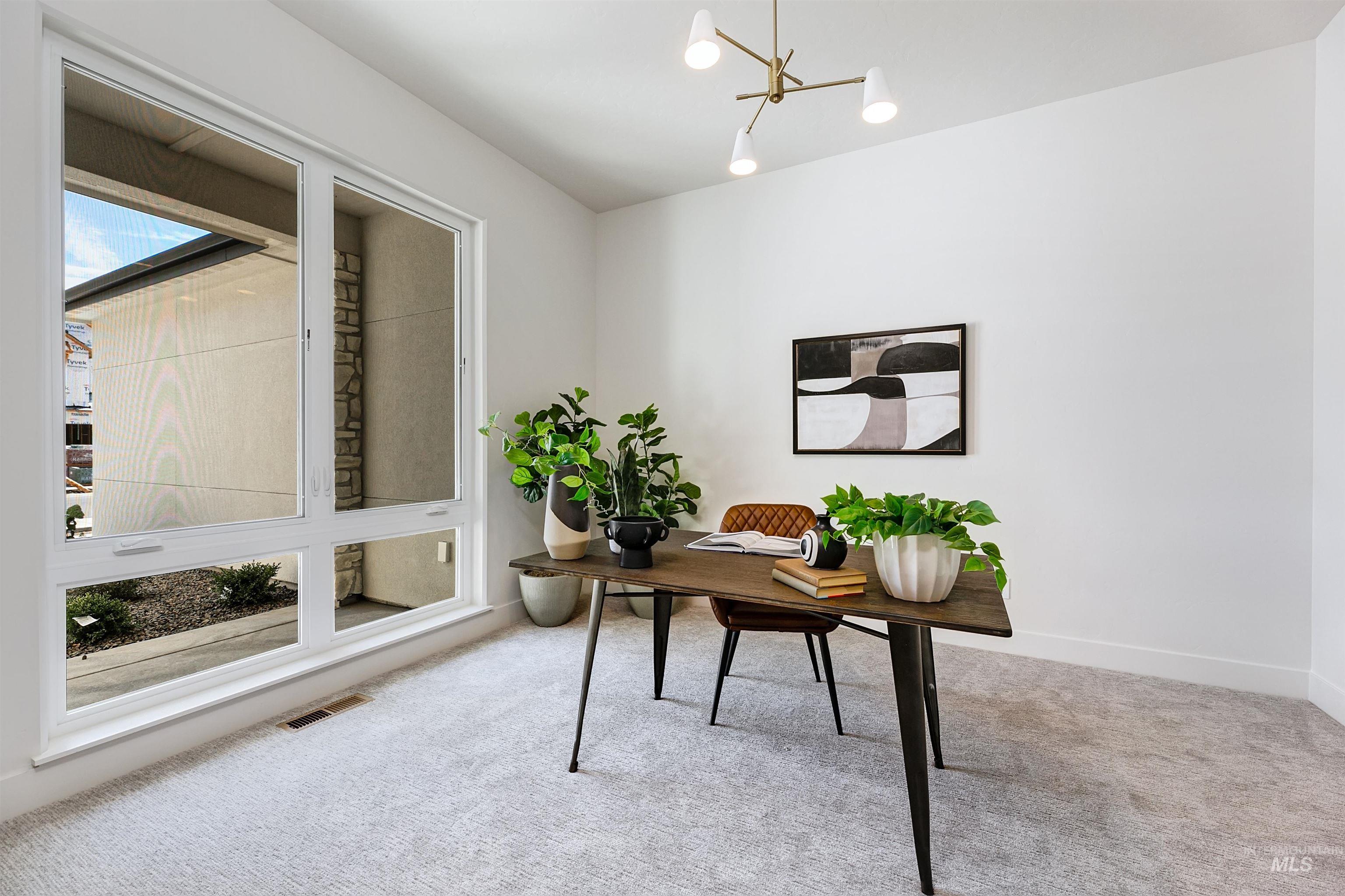 Light-filled room featuring a large multi-pane window, neutral-toned carpeting, a contemporary ceiling light fixture, and white painted walls